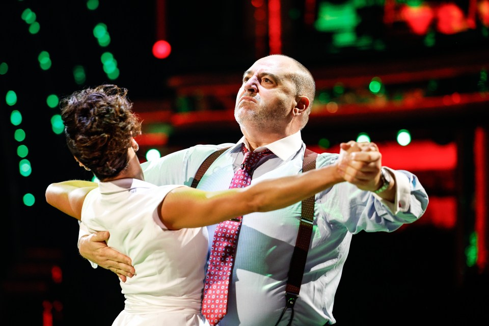 a man in suspenders is dancing with a woman in a white dress