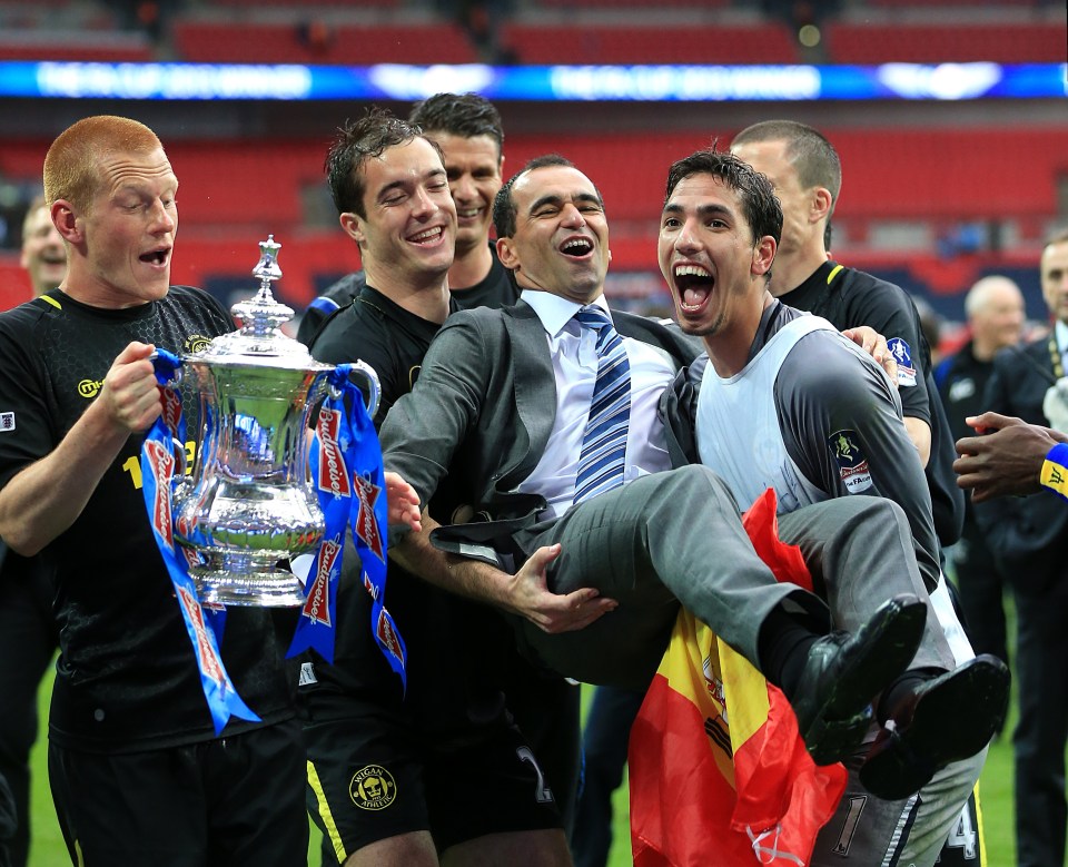 Soccer players celebrating with the FA Cup trophy.