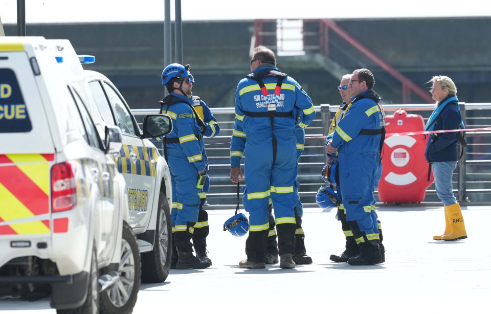 Coast guard members and a bystander near coast guard vehicles.