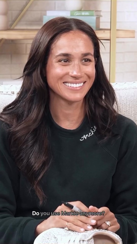 Meghan Markle on a podcast, signing a pair of shoes.