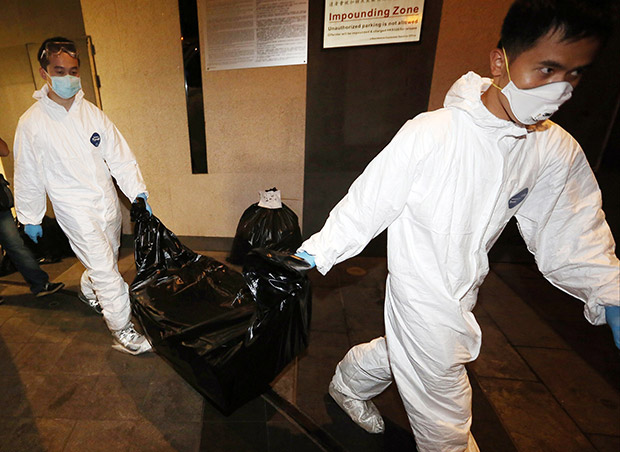 This picture taken on November 1, 2014 and released on November 2, by the South China Morning Post newspaper to AFP shows workers from the Food and Environmental Hygiene Department carrying the remains of a woman from the J Residence flat, after the grisly discovery of two female corpses, including one in a suitcase in the Wanchai district of Hong Kong. Hong Kong police were on November 2 questioning a 29-year-old British man who works for Bank of America Merrill Lynch after the discovery of the two corpses.