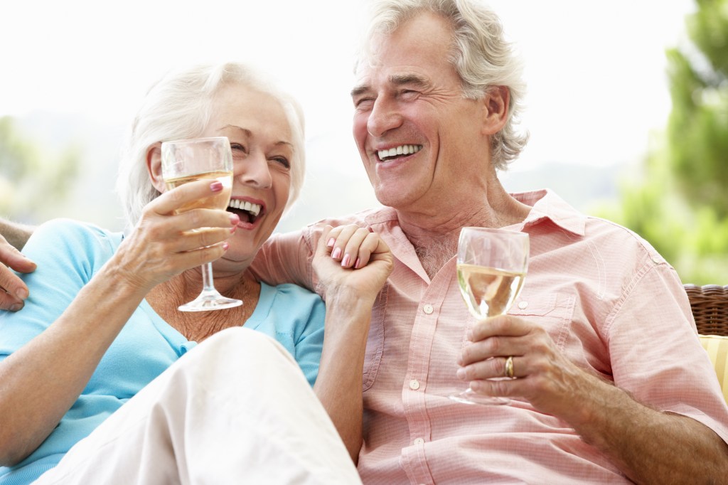 Senior Couple Sitting On Outdoor Seat Drinking Wine