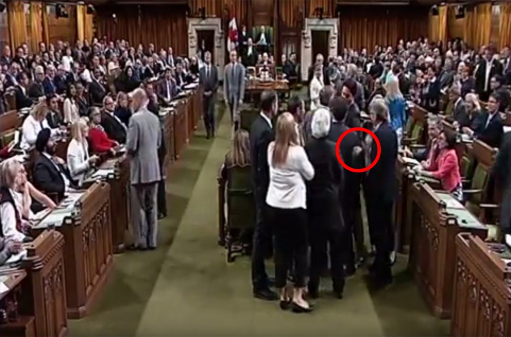 Canada's Prime Minister Justin Trudeau puts his hand on an opposition politician and leads him away