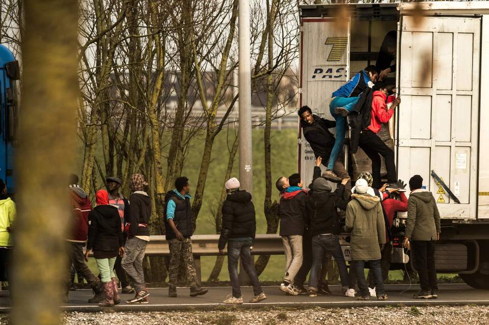 Migrants and refugees enter the trailer of a truck on the site of the Eurotunnel in Calais