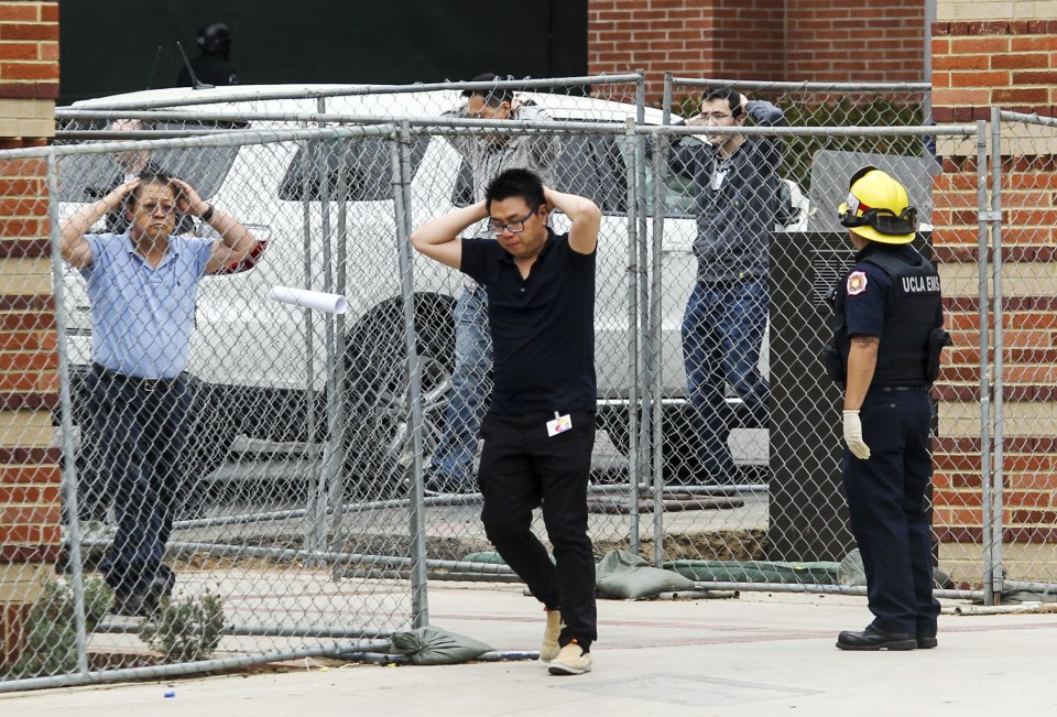 Students are escorted away by emergency personnel and ordered to keep their hands visible