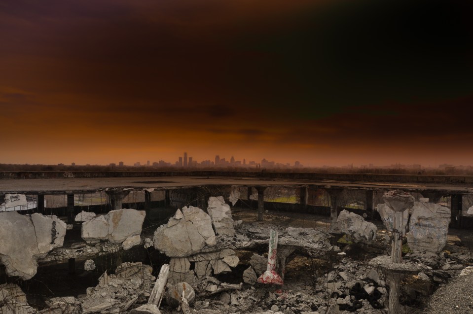 The remains of a crumbling car park overlook a unnamed city in the distance