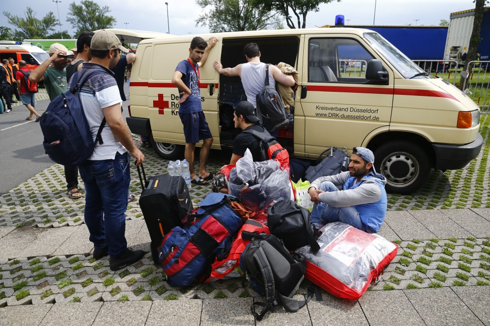 Migrants rest on the ground after exhibition halls used as refugee camps were damaged in a fire in Duesseldorf