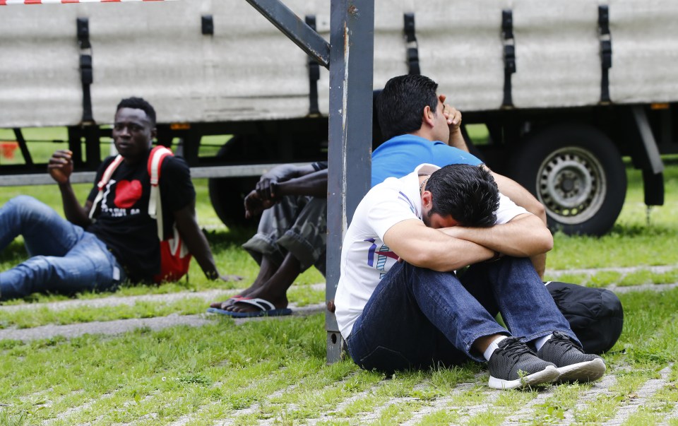 Migrants rest on the ground after exhibition halls used as refugee camps were damaged in a fire in Duesseldorf