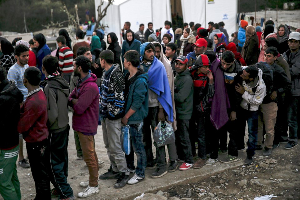 Refugees and migrants line up for a food distribution at the Moria refugee camp on the Greek island of Lesbos