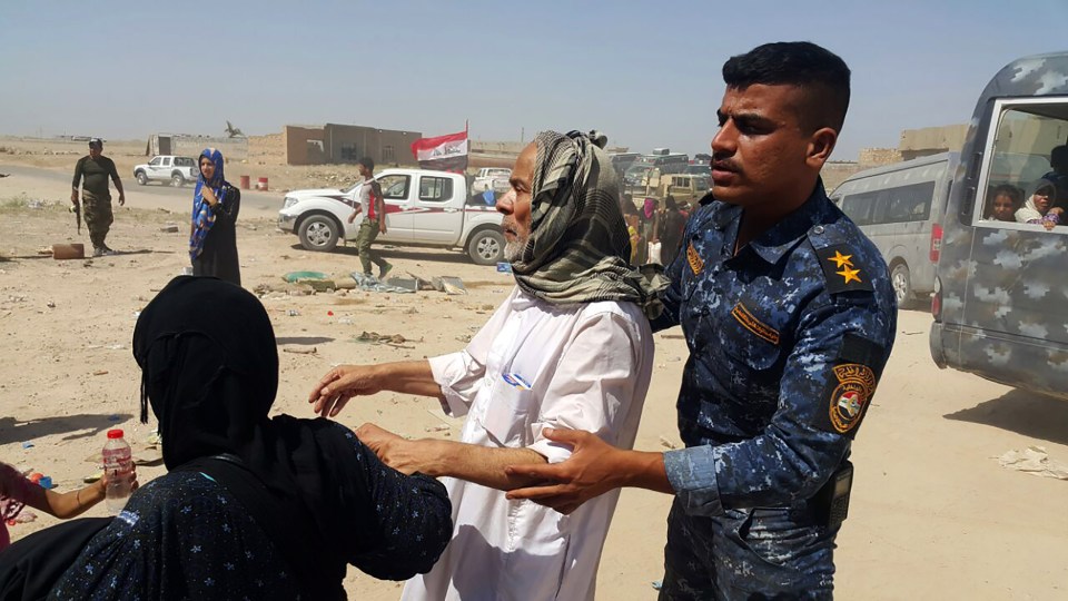 Members of the Iraqi security forces assists civilians, who fled their homes in and around Fallujah due to fighting between Iraqi government forces and the Islamic State