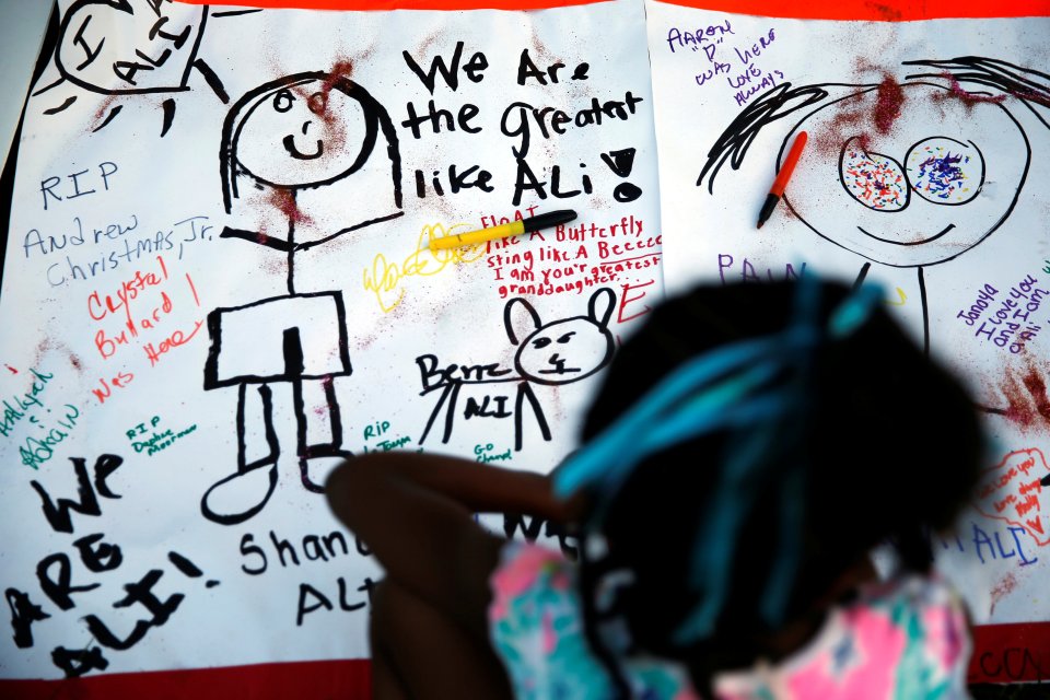 Children sign memorial outside childhood home of late boxing champion Muhammad Ali in Louisville