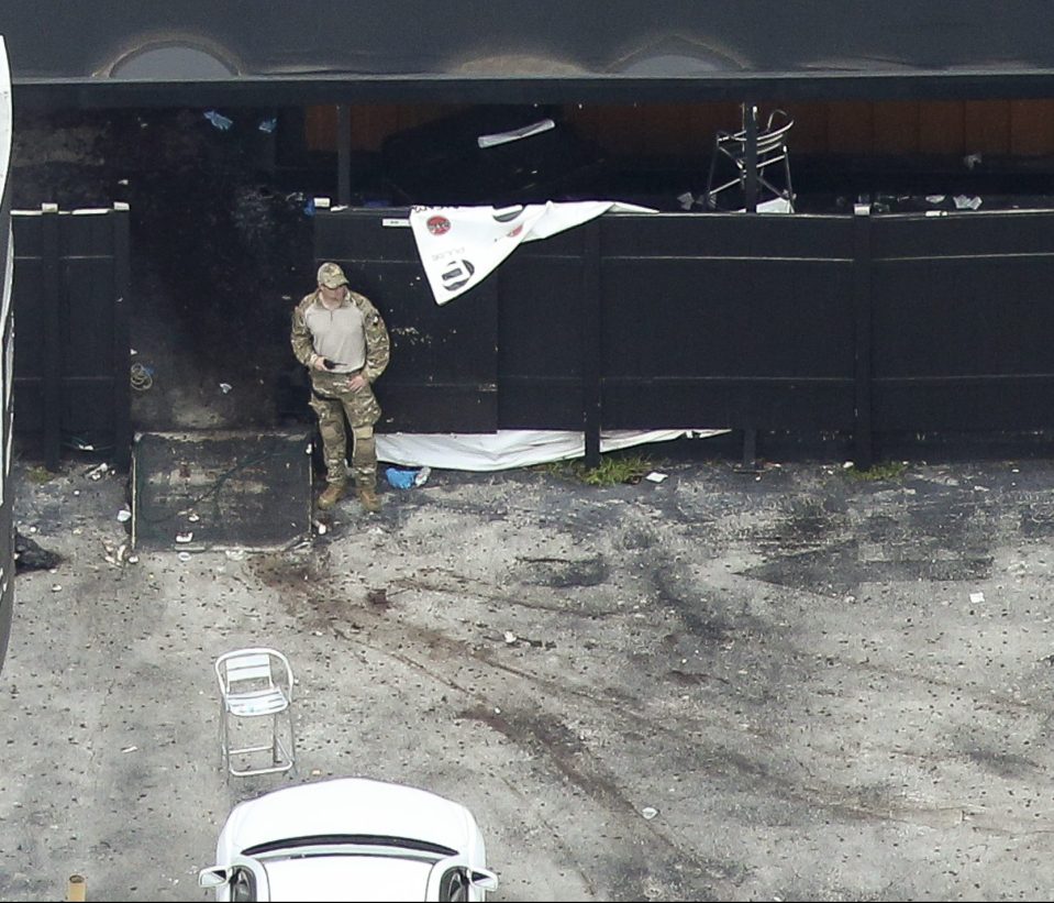 An officer surveys the bloody scene outside the nightclub