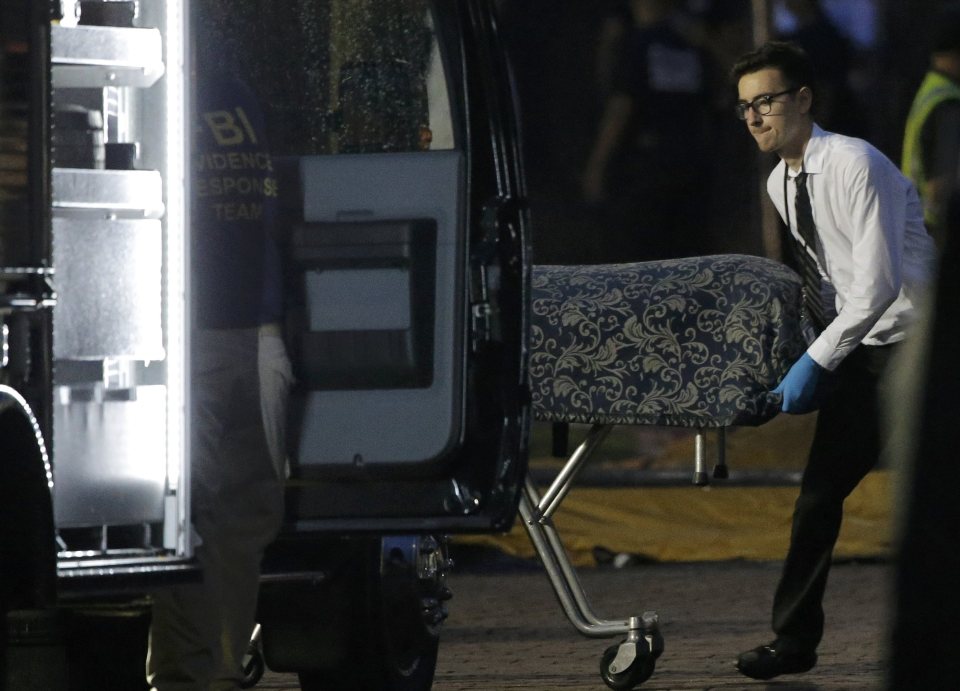 Police forensic investigators work at the crime scene of a mass shooting, a body is removed at the Pulse gay night club in Orlando