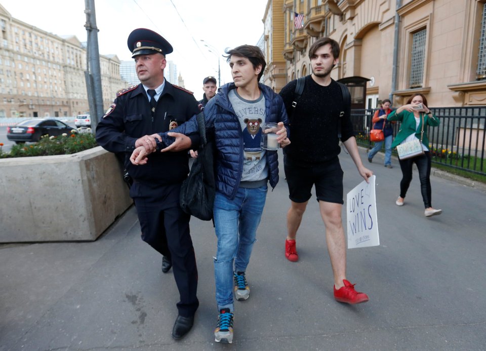 A Russian police officer detains a man as he intended to place a candle and a placard for the victims of the shooting at a gay nightclub in Orlando in front of the U.S. Embassy in Moscow