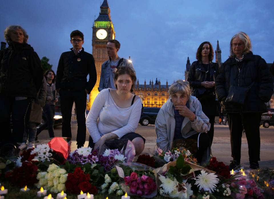 People place floral tributes and candles