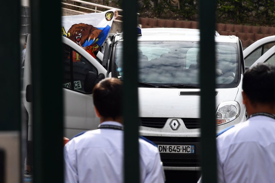 A Russian supporter pulls out his nation's flag as he exits a van during deportation 