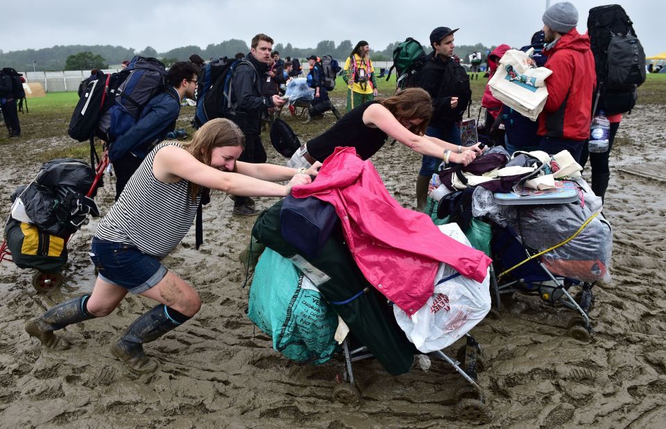 Two revellers push their gear through the mud