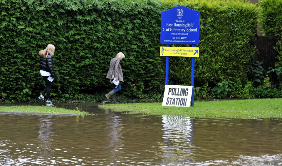 People make their way along a flooded path as they arrive to vote at the polling station in East Hanningfield, Essex as torrential downpours and flooding have swamped parts of London and the South East