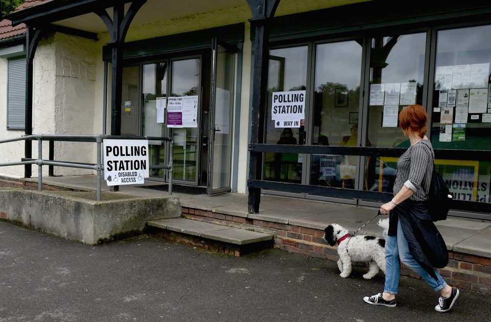 A woman and her dog, Archie, head to their polling station in Farthing Downs, Coulsdon