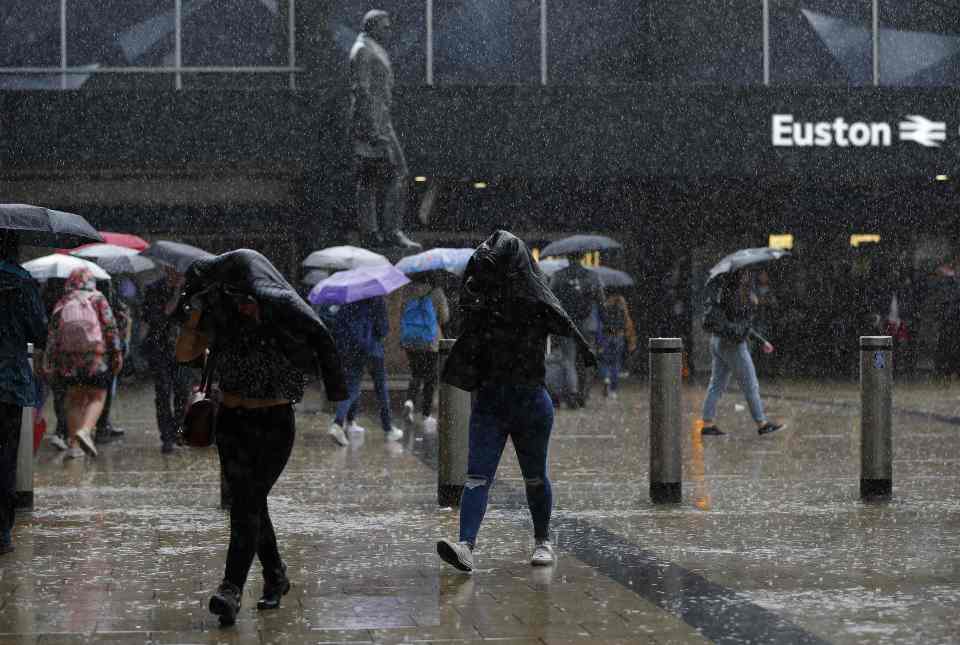Commuters use coats and umbrellas to she