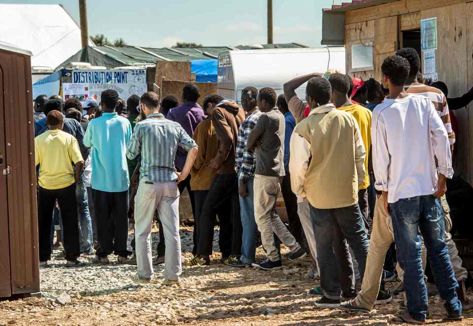 Migrants queue at a distribution point inside the 'Jungle' camp for migrants and refugees in Calais on the day after Britain voted to leave the EU