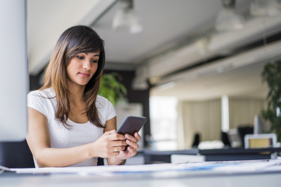 Beautiful businesswoman using smart phone at desk