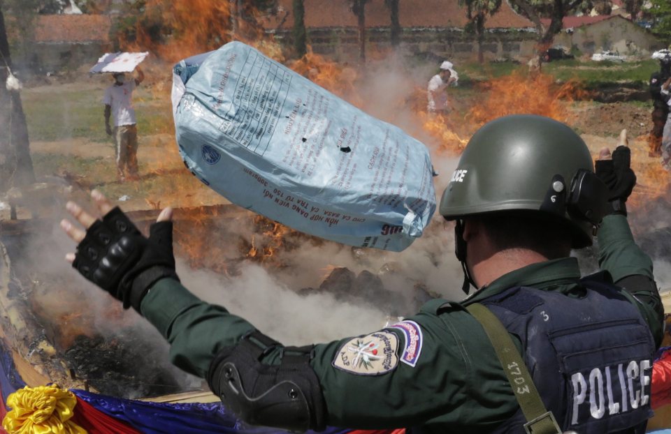 epa05391495 A Cambodian police officer throws a bag of marijuana on a fire during a drug destruction ceremony in Phnom Penh, Cambodia, 26 June 2016. The Cambodian National Authority for Combating Drugs destroyed 67.41 kg of methamphetamine, 0.345 grams of heroin, 1.5 kg of marijuana oil and 1494.85 kg of dried marijuana after they seized them from drug traffickers