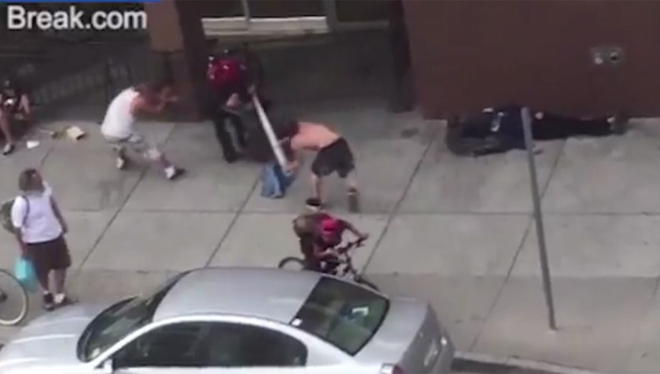 The assailant runs across the street and brings the pipe down on another helpless man's shoulders