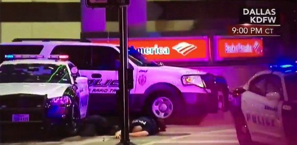 A policeman lies on the ground after apparently being shot during a sniper attack in Dallas 