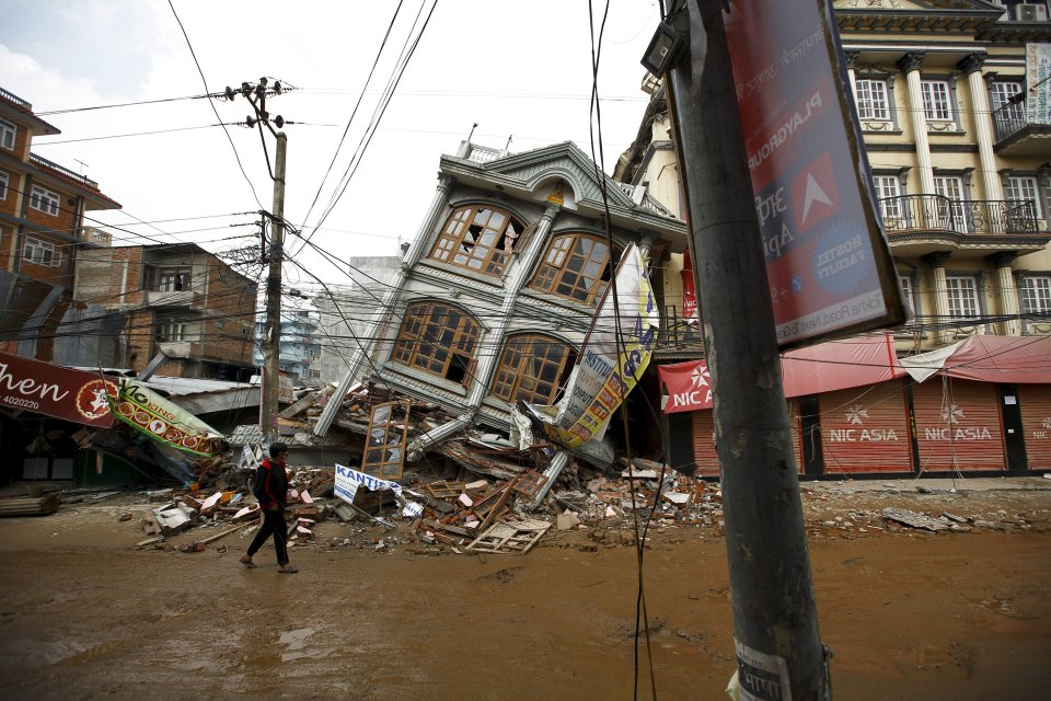 Man walks along the street near a collapsed house following Saturday's earthquake in Kathmandu, Nepal