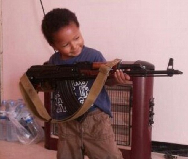 'Jihadi Junior' Isa Dare poses with an AK-47 as a report reveals ISIS are training a new generation of killers