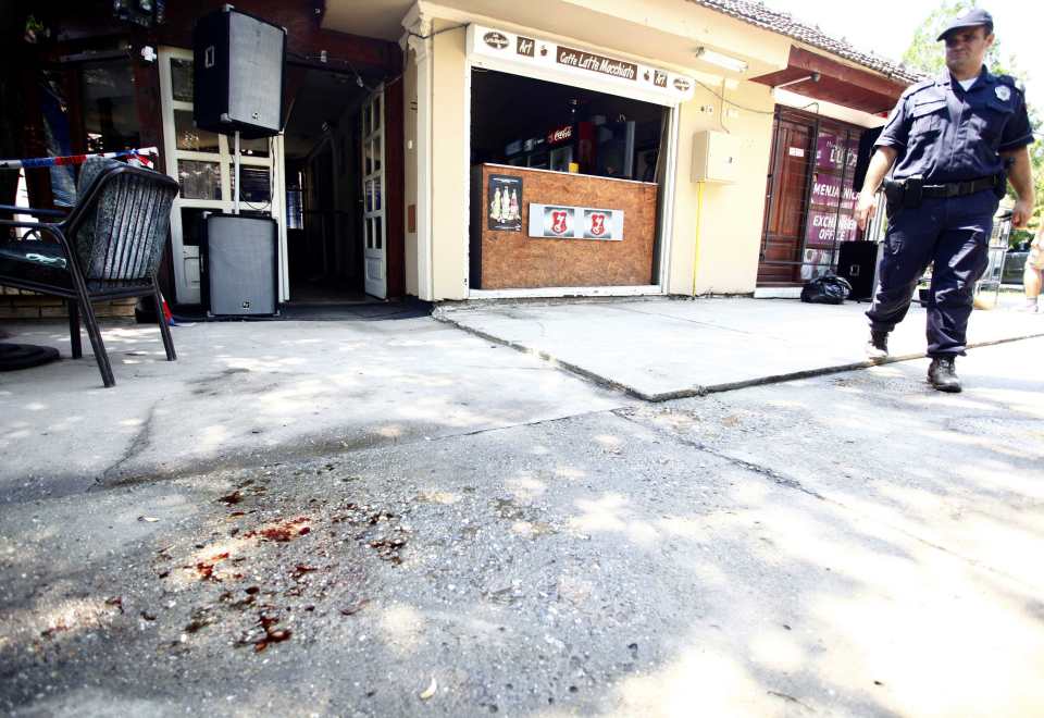 A police officer walks past the blood-soaked ground at the scene of the shooting