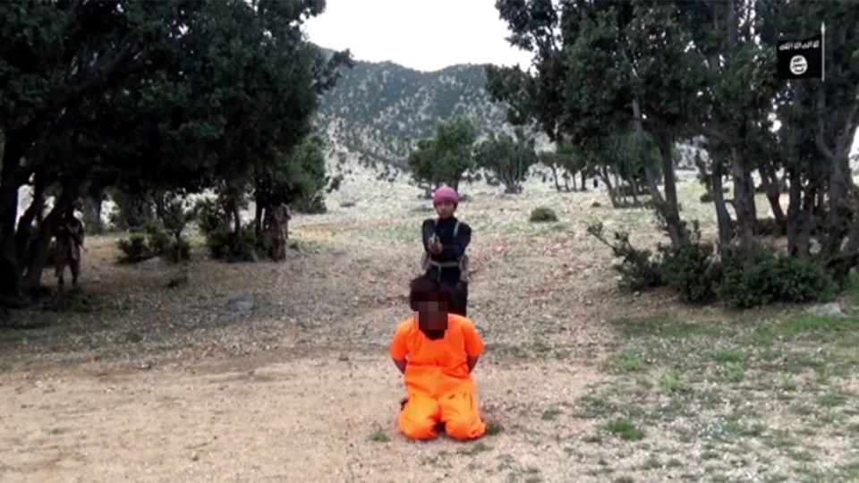 An ISIS child soldier takes aim at the prisoner's head during the propaganda video