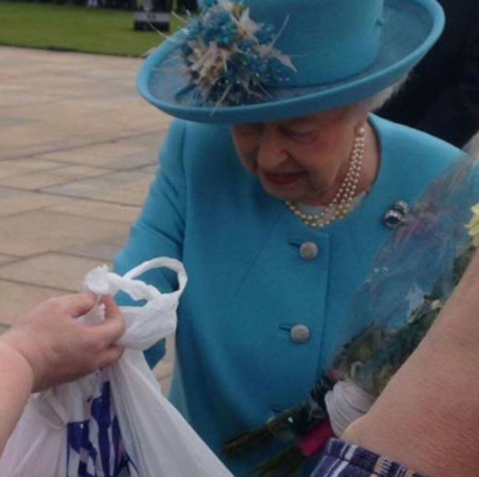 The Queen is handed a carrier bag from discount store B&M containing toys for her great-grandchildren Prince George and Princess Charlotte