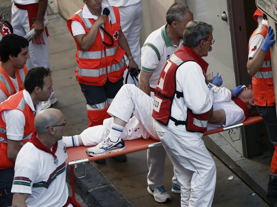 A wounded runner is quickly taken from the street as the festival continues
