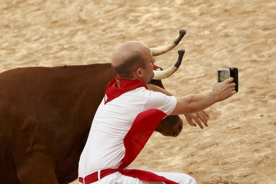 What a shot! A runner goes for the ultimate selfie with a raging bull during the first race of the eight-day festival