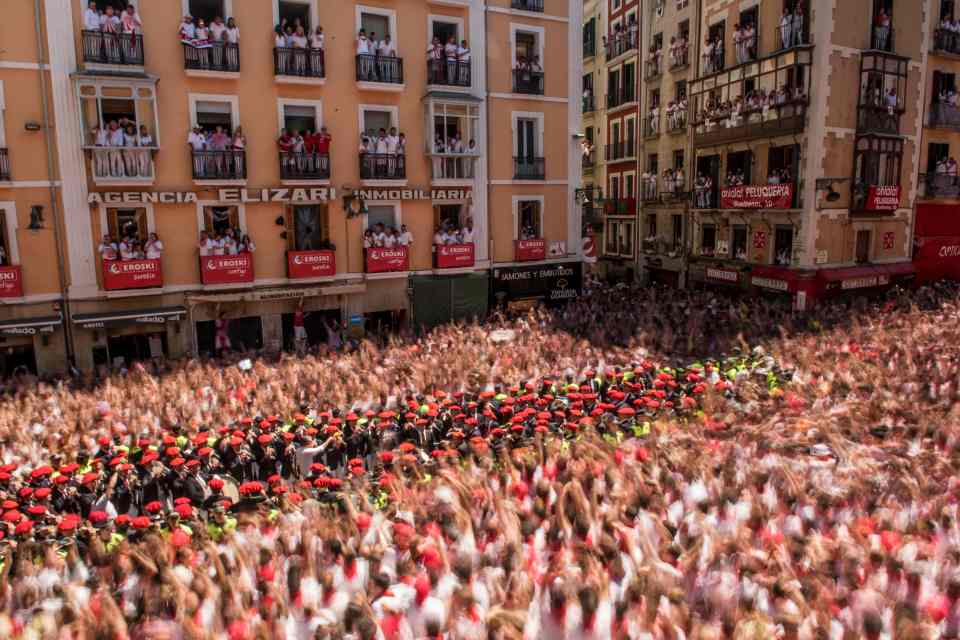 A band surrounded by police plays as revellers celebrate the 'Chupinazo' 