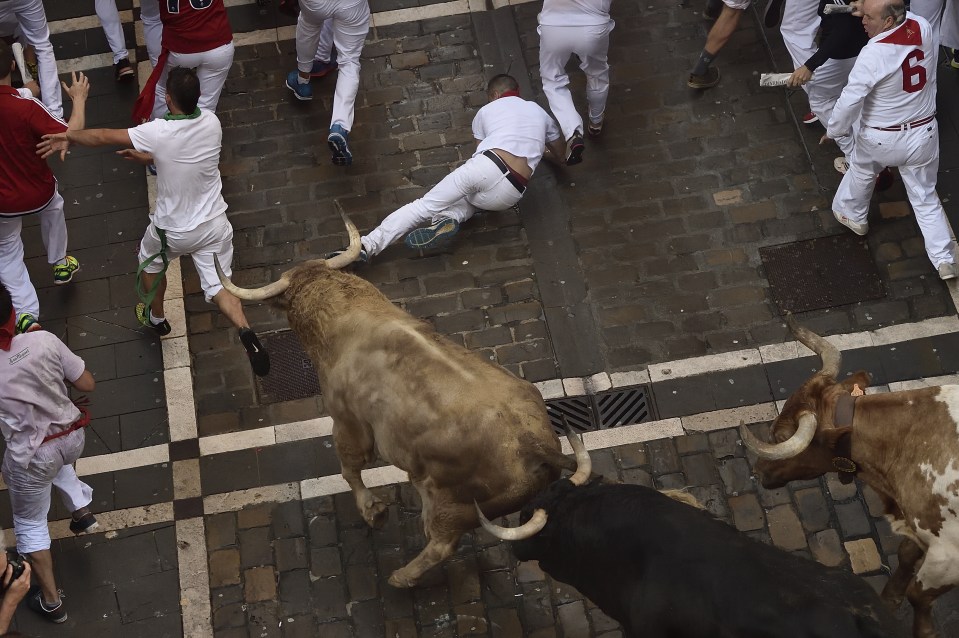 One of the runners falls over as he tries to escape the raging bull ploughing through the crowd