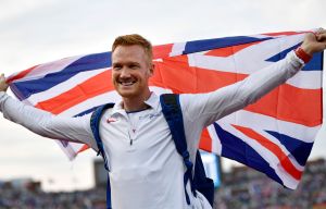 Britain's Greg Rutherford celebrates with the British flag after winning the men's long jump final during the European Athletics Championships in Amsterdam at the Olympic Stadium on July 7, 2016. / AFP PHOTO / FABRICE COFFRINIFABRICE COFFRINI/AFP/Getty Images