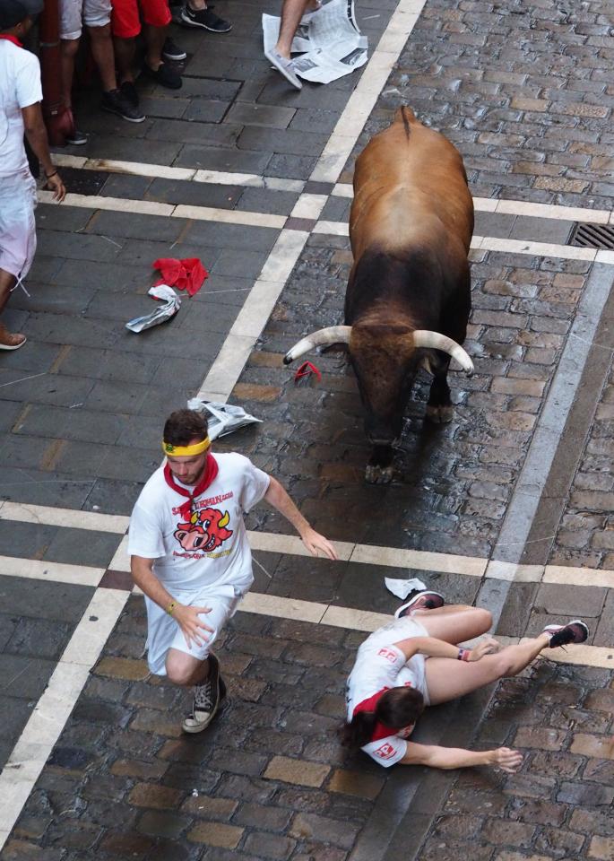 Runners try to escape the horns of a bull with one fallen reveller scrambling to get off the ground