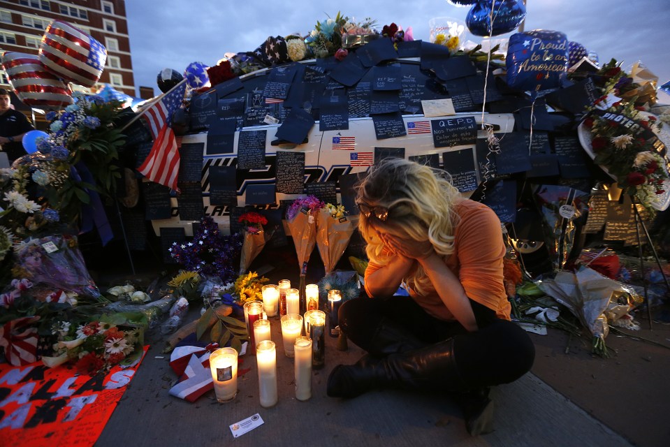 Tasha Lomoglio, of Dallas, cries after lighting candles at a makeshift memorial in honor of the slain Dallas police officers in front of police headquarters in Dallas, Saturday