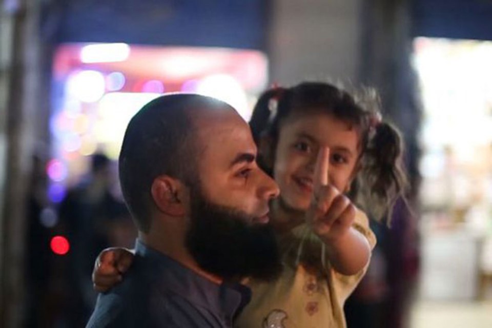 A young girl and he father enjoy the bizarre show in ISIS-controlled Raqqa