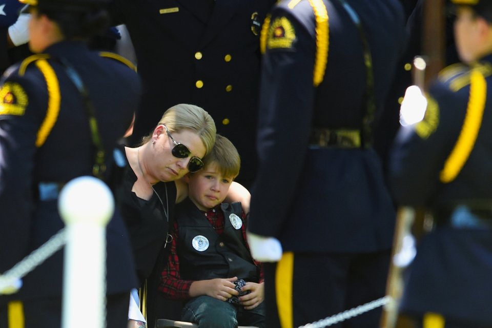 Katrina Ahrens sits with son Magnus Ahrens during the burial ceremony of her husband, Dallas Police Department Senior Corporal Lorne B. Ahrens in Dallas