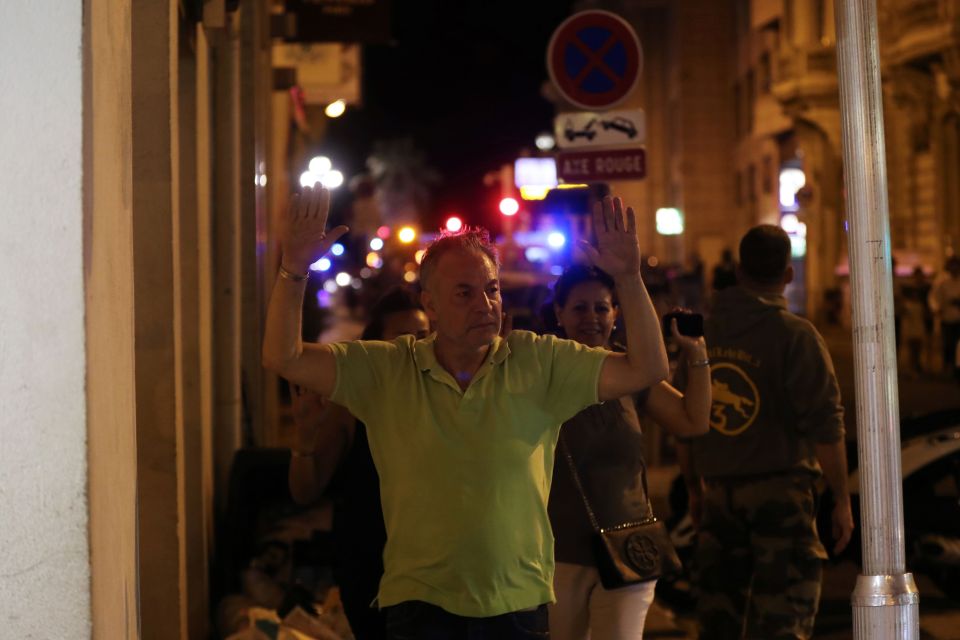 A man walks with his hands up as police