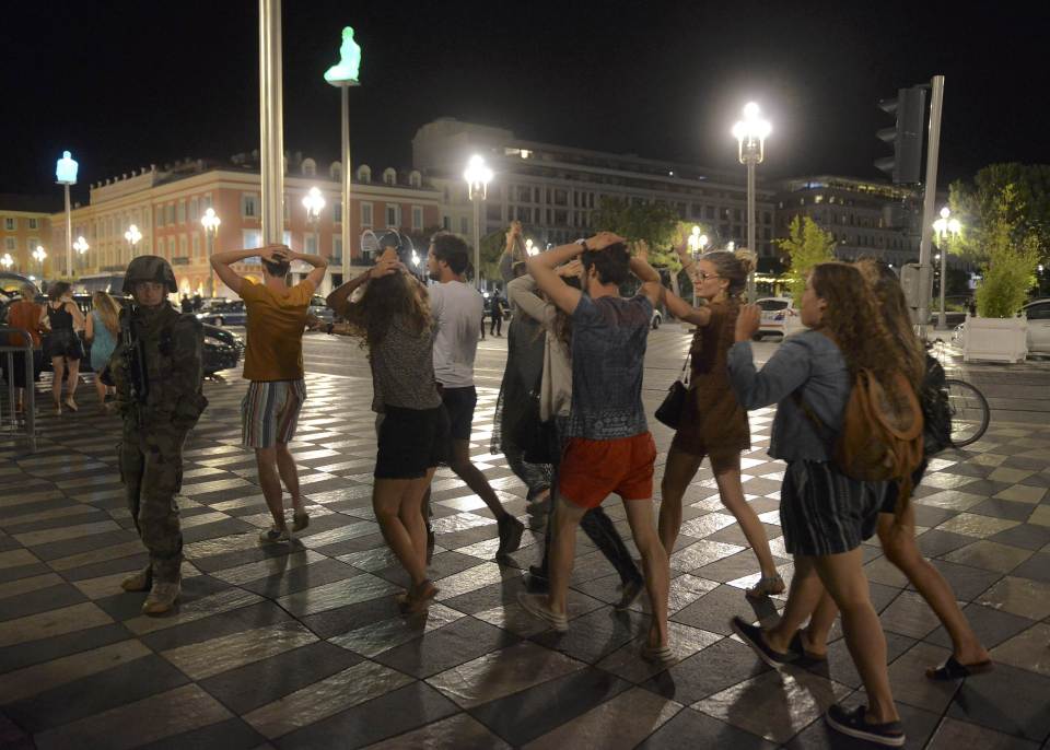 People cross the street with their hands on thier heads as a French soldier secures the area after at least 60 people were killed in Nice when a truck ran into a crowd celebrating the Bastille Day national holiday