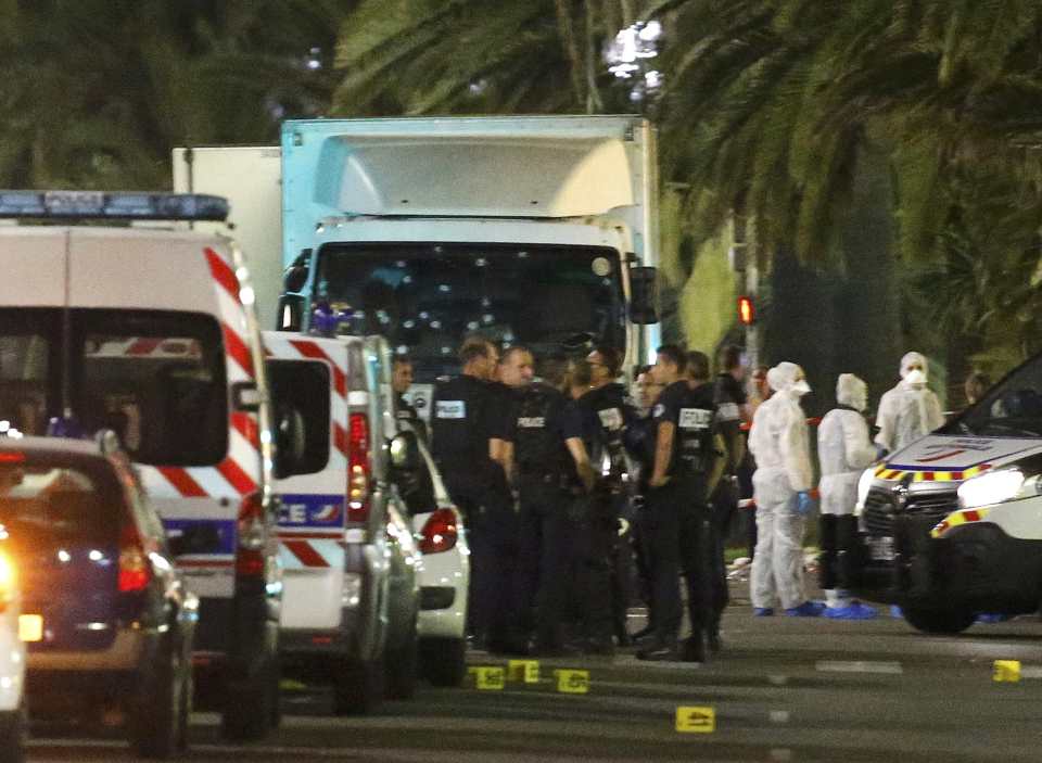 French police forces and forensic officers stand next to a truck that ran into a crowd celebrating the Bastille Day national holiday on the Promenade des Anglais killing at least 60 people in Nice