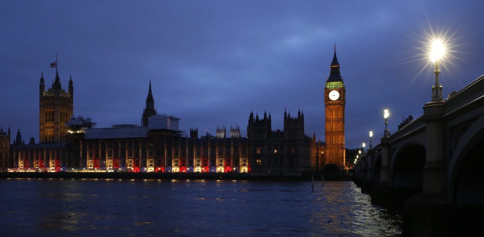 People look on as the Palace Of Westminster is adorned in blue, white and red to show solidarity with the French nation
