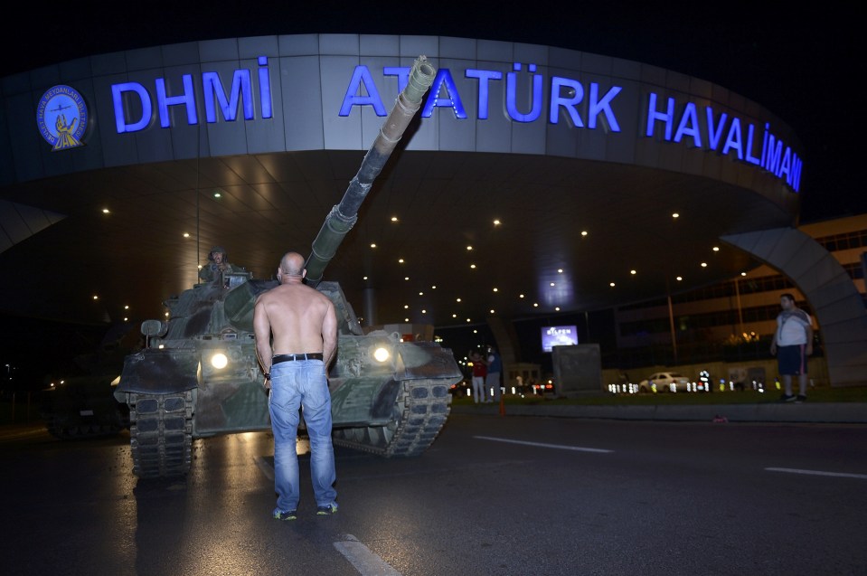 A man stands in front of a Turkish army tank at Ataturk airport 