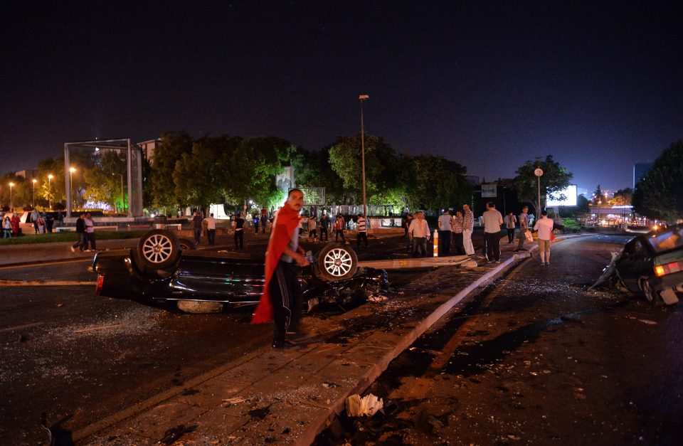 A man stands near a burned car in Ankara