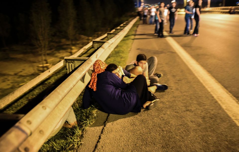 People huddle together as soldiers and protesters clash on the streets